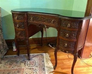 Ornately carved antique wooden desk with glass top