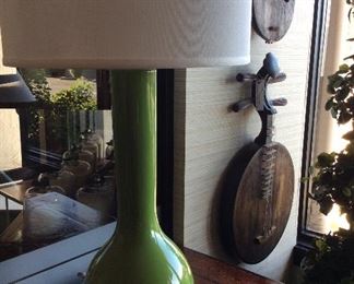 Contemporary green lamp paired with antique string instruments hung on the wall.  Eclectic and interesting!
