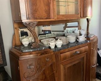 Antique sideboard with marble top and hutch in medium wood tones with wood carvings.