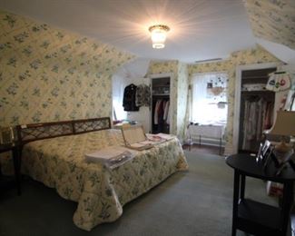The master bedroom includes a king size bed, two round black end tables, beautiful linens, sewing, clothing and more.  