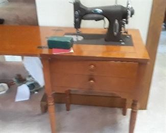 White sewing machine with accessories in cabinet