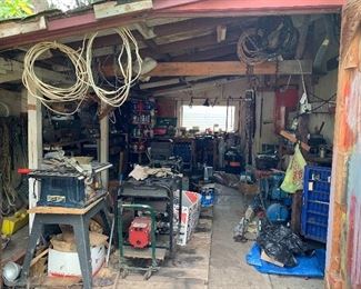 A detached garage full of tools, parts, cabinets and other 