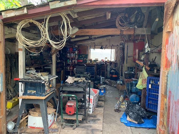 A detached garage full of tools, parts, cabinets and other 