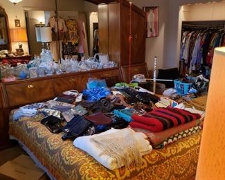 master bedroom, 2 full closets of vintage clothing, a king bed and dresser covered with purses and belts.