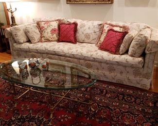 Floral upholstered sofa with an Italian brass coffee table with glass top