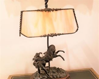Bronze table lamp with a male figure and a horse and a slag glass shade