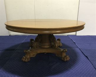 A HANDSOME PROFUSELY CARVED WALNUT DINING TABLE IN THE RENAISSANCE REVIVAL STYLE.  The round top enclosed by an Ogee molded frieze and opening to accommodate 6 leaves; the carved columnar standard enclosed by acanthus carved volutes and resting on four massive carved lion claw feet.