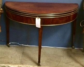 "A HANDSOME ENGLISH REGENCY BRASSMOUNTED
MAHOGANY TRIPLE-TOP CONSOLE
Circa 1810
The two demilune tops opening to a third top inset with green
felt; the apron embellished with tubular brass molding; the
tapered square legs mounted in brass casters.
Condition: Very good."