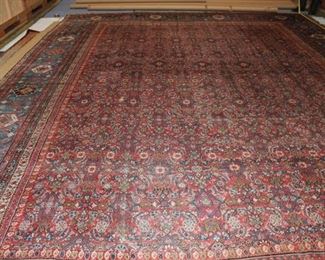 "A PERSIAN HAND-KNOTTED WOOL PILE LARGE
CARPET
Origin or design: Mahal
Period: Modern
Description: The olivine field detailed in a dense floral
diaper possibly in a variation of the “Herati” pattern and
executed in predominant hues of white and brick red; the
wide blue border interrupted by alternating brick red and
white cartouche medallions, and enclosed by seven floral
guards.
Construction: Fairly loosely Senneh-knotted wool pile on a
cotton foundation; the selvedge overcast in brown wool.
Condition: Very good."