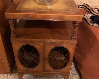 Weiman Mahogany & Leather Top End Tables, Solid wood construction, tooled leather tops, 2 swing cabinet doors with metal sunburst grills, tops raised on column supports, finished backs, great American craftsmanship. Early to Mid 1900s, American
27" H x 18" W x 22.5" D