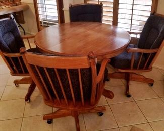 round wooden table with 4 rolling chairs. Includes 2 additional table leafs