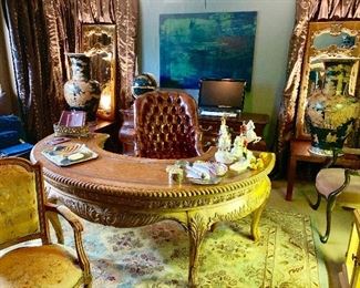 The large circular desk is flanked by a pair of brown temple jars and a pair of French mirrors, the desk chair is from Hickory Chair Company 