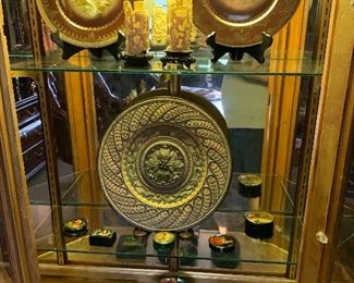 The contents of the display cabinet are as follows: top shelf two fowl plates by Royal Vienna and a pair of as is ivory cuttings. The next two shelves hold a collection of Russian Lacquer boxes. 