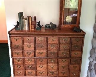Antique library filing cabinet; sampling of the antique books and bookends for sale; antique clock.