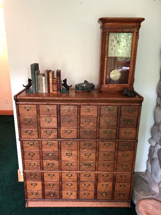 Antique library filing cabinet; sampling of the antique books and bookends for sale; antique clock.