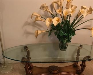 GOLD TONE WOOD HOLDING GLASS ON OVAL COFFEE TABLE/ CALLA LILY ARRANGEMENT IN CUT TO CLEAR VASE