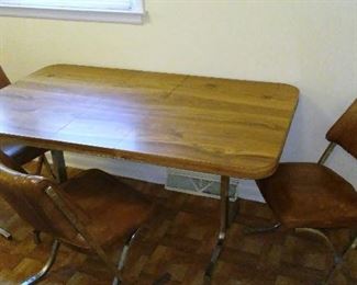 Vintage faux-wood-grain and chrome kitchen table with three matching vinyl-covered chairs.