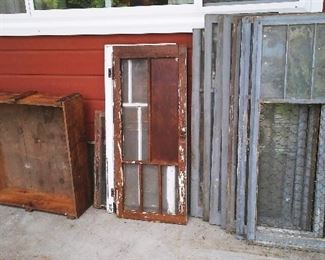 A selection of vintage windows and frames with loads of old paint patina and a large vintage shipping crate.