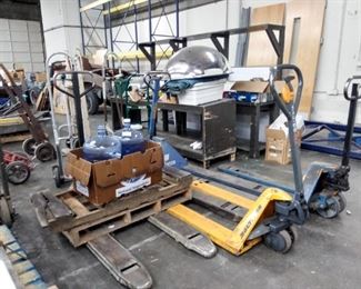 Example of Industrial Equipment ...Pallet Jacks Hand carts / trucks some wooden vintage .  One of 2 Safety mirrors  2 wooded work stations  Some heavy duty metal shelving in back along wall   etc.