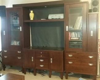 Very nice heavy wood entertainment center with doors and drawers for storage. Hold larger tv and has a black curtain in the back making plugging easier.