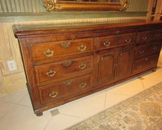 Offered at $7000. Oak six drawer plus two door North Wales dresser base. Superb example of the classic late 18th century North Wales cupboard dresser base, circa 1790. Excellent top with banded edges. Two rows of four drawers, three top drawers, plus two cupboard doors in the center with attractive shaped panels. Excellent color and condition, cleaned and waxed. (22"d x 76.75"l x 31"h) ~ Please send inquiries via text to 251.525.0966 and reference the photo number.