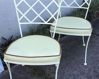 A pair of iron chairs with upholstered seats
