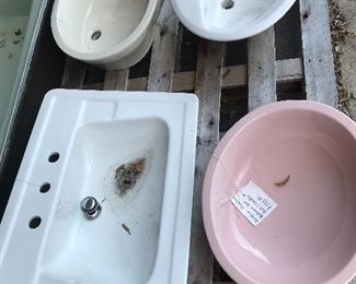 Pink oval sink along with beige and white sinks
