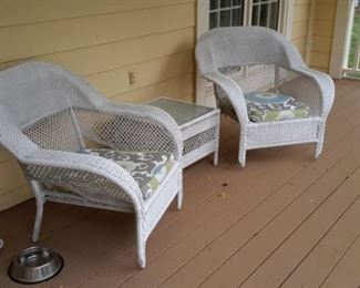 Two white wicker armchairs and side table with glass topper.