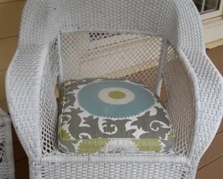 Two white wicker armchairs and side table with glass topper.