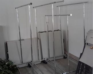 Six (two not pictured) adjustable clothing racks on casters.