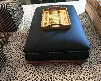 Upholstered ottoman (black flannel) with wooden feet.