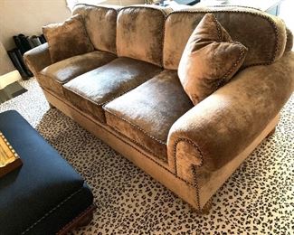 Three cushion rolled arm custom sofa with nail head trim and round wooden feet.