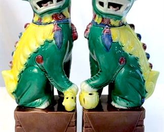 Pair of multi-color polychrome glazed ceramic  foo dogs. 1 has paw on ball, the other has  paw on small creature. Bright yellow, green,  and rose taupe tones. Each is stamped 87 on  underside, along with impressed numbers and symbols. Each measures approx 8.5 inches in  height by 2.6 inches in width by 1.8 inches  in depth. Vintage ceramic foo dogs, temple  lions, guardian lions, polychrome glaze  ceramic foo dogs, Chinese East Asian Decorative Arts, Decorative tabletop display  accessories, collectible foo dog figurines,  sculptures, statues, vintage ceramic pottery.  asian arts and crafts,