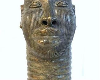 African Art Metal male head sculpture in the  style of The Bronze Heads from Ife. Appears  to be bronze metal, possibly other metal  alloy. Sculpture features slightly larger  than life-size male head with ribbed ring style texture in the neck and etched striped  texture in face. Pierced holes along the  brain case, possibly due to the casting  process. Measures approx 16 inches in height  by 5.75 inches in diameter at base. Some wear  like discoloration consistent with age.  There is dent in top of head, as noted in  photo. African Art, Tribal Art, African  sculpture, ethnographic Art, African folk  art, African sculpture figural, figurine, decorative art, collectible African arts. ‘Ife is today regarded as the spiritual  heartland of the Yoruba people living in  Nigeria, the Republic of Benin and their many  descendants around the world. It is rightly regarded as the birthplace of some of the  highest achievements of African art and  culture, combining technical accomplishment  with 