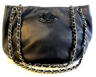 Authentic CHANEL luxury Designer soft leather  satchel handbag. Deep navy blue tone leather  with silver tone metal details in chain  strap and Chanel logo On exterior. Snap  button closure. Leather label in interior reads for Chanel, Made In France. Interior  zipper pocket and side pockets for phone and  smalls. Handbag measures approx 10 inches by  14.5 inches in width. Drop strap measures  approx 15 inches in length. Used condition with light wear and scuffs to leather. Luxury  designer handbag, shoulder bag, satchel bag,  purse, tote bag, carry-all bag, designer  fashion accessory, designer handbag. 