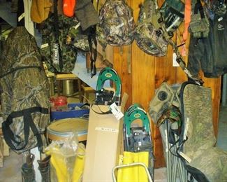 A WALL FULL OF SPORTING EQUIPMENT.  NOTICE THE NEW STILL IN BOX AND WRAPPER OF SNOWSHOES AND BOOTS.  CLOTHING, BOWS, BOW CASES AND GEAR