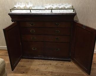 Ships cabinet w/3 drawers and 1 deep double drawer. Carrerra marble topped with a brass tubing. Mahogany.