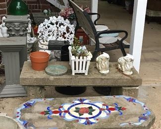 Foreground is a unique tile-laid cement bench - chair in background is cast iron and very heavy