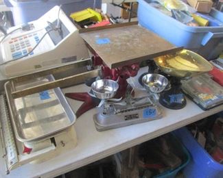 A variety of old vintage scales and a cash register.
