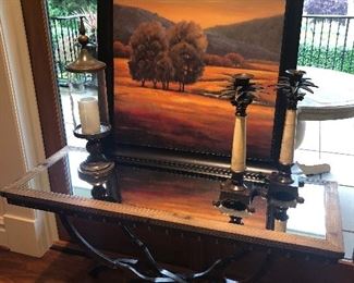 Wood and metal console table with mirror top, shown with palm tree candlesticks and framed print