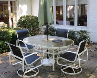 Glass top table with four swivel chairs and umbrella.  