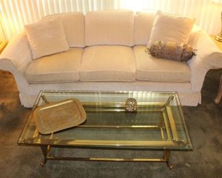 Cream colored quality built custom sofa shown with brass base, glass top coffee table.  