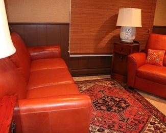 Antique handknotted Persian rug, midcentury red leather sofa w/ matching chair and blanc de chine lamps