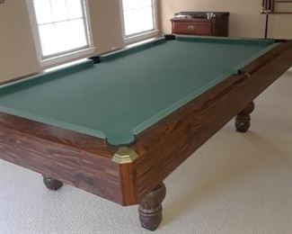Big pool table, pool sticks in background