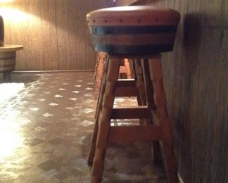 Four wooden bar stools with rust leather seats.