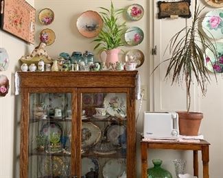 antique oak china cabinet/ display case, end table, floral plates, vintage salt and pepper shakers, antique glassware, metal trays