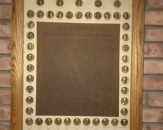 This is a picture of the US constitution surrounded by coins depicting the signers.