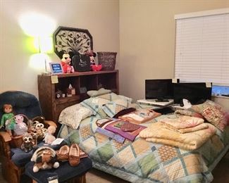 Master bedroom with bedding, dolls, Disney, moccasin slippers, TVs, etc