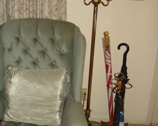 Upholstered wing chair, one of a pair, brass floor lamp, brass umbrella stand.