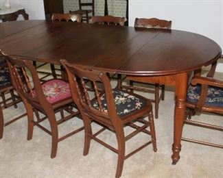 Antique Round/Oval Table with 6 leaves on Turned legs and original Casters 94” L x 45” W x 30” H shown with 8 (7 Side and 1 Arm) Chairs with various Floral needlepoint seat cushions 